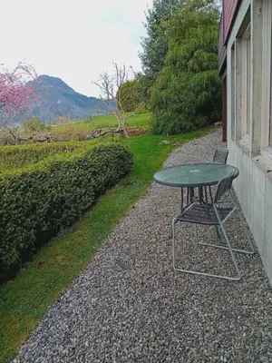 a table and a chair sitting next to a house at Sandeidfjorden overnatting in Sandeid