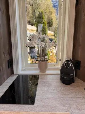 a vase of flowers sitting on a window sill at Fjord Cabin with Panoramic View & Private Balcony in Luster