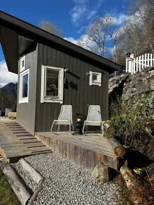 a tiny house with two chairs on a wooden deck at Fjord Cabin with Panoramic View & Private Balcony in Luster
