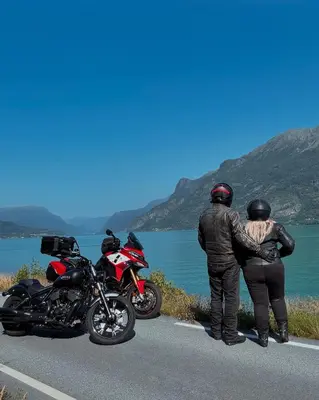 two people standing next to two motorcycles on a road at Fjord Cabin with Panoramic View & Private Balcony in Luster