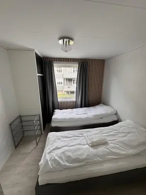 a bedroom with two beds and a window with a chandelier at Trolltunga Apt for up to 5 people with balcony in Tysso