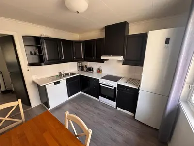 a kitchen with black cabinets and a white refrigerator at Trolltunga Apt for up to 5 people with balcony in Tysso