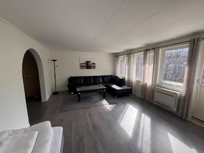 a living room with a black leather couch and windows at Trolltunga Apt for up to 5 people with balcony in Tysso