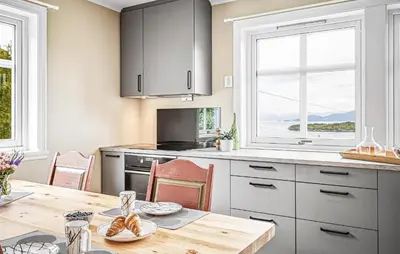 a kitchen with a wooden table and a kitchen with windows at Nice Home In Lundegrend With Wifi in Grimsland
