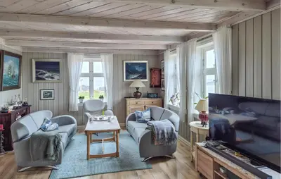 a living room with two chairs and a tv at Awesome Home In Bekkjarvik in Bekkjarvik