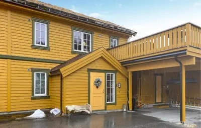 a yellow house with a cow standing in front of it at Beautiful Home In Bjorli With Wifi in Bjorli