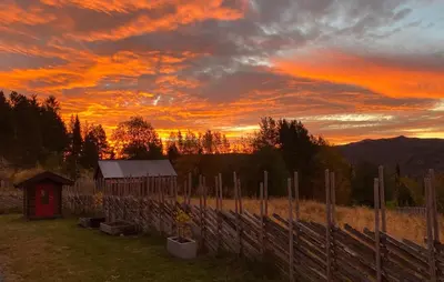 a sunset over a field with a fence and a barn at Gorgeous Home In Oppdal With Wifi in Oppdal
