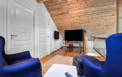 a living room with blue chairs and a flat screen tv at 4 Bedroom Stunning Home In Hebnes in Hebnes