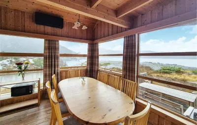 a dining room with a table and chairs and windows at Lovely Home In Masfjordnes With Sauna in Masfjorden