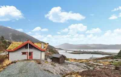 a small house on a hill next to a body of water at Cozy Home In Masfjordnes With Sauna in Masfjorden