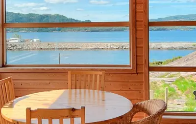 a table and chairs in a room with a large window at Cozy Home In Masfjordnes With Sauna in Masfjorden