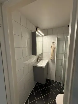 a white tiled bathroom with a sink and a mirror at Apartment in Bergen in Bergen