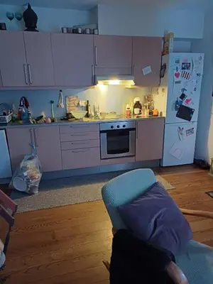 a kitchen with white cabinets and a blue chair in it at Sentrums nærsentrum tur og sjø på hundvåg in Lii