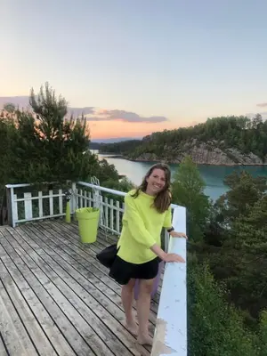 a woman standing on a deck with a view of the water at Seaside Cabin with panoramic view in Bømlo