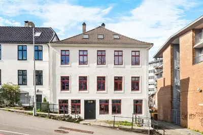 a white building with red windows on a street at Scandinavian Design in Authentic Nordnes in Bergen