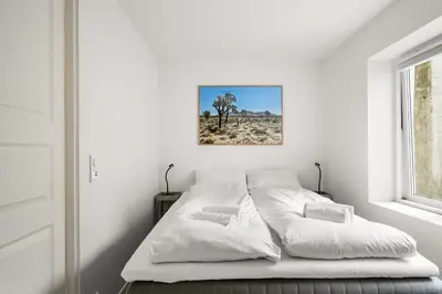 a white bedroom with a bed and a window at Scandinavian Design in Authentic Nordnes in Bergen