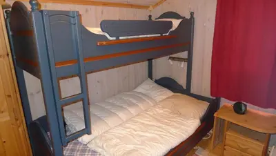a bunk bed in a room with a ladder and a bed at Skeitunet in Svingvoll