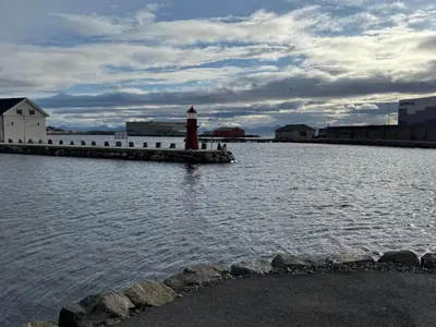 a lighthouse in the middle of a body of water at Leilighet på Harøya in Ålesund
