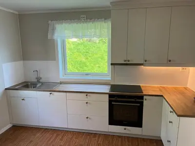 a kitchen with white cabinets and a sink and a window at Flo Lake House in Stryn