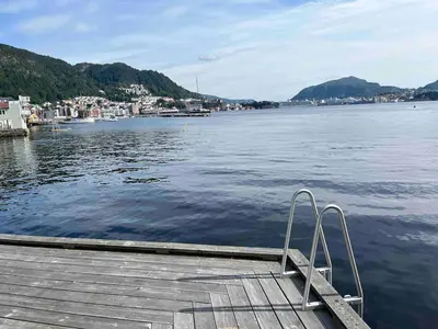 a wooden dock with a bench on the water at Nice apartment in modern complex near Old Bergen in Bergen