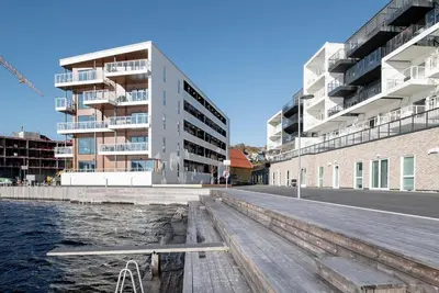 a building next to the water with a dock at Nice apartment in modern complex near Old Bergen in Bergen