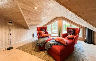 a living room with two red chairs in a attic at Stunning Home In Sjusjøen With Sauna in Sjusjøen