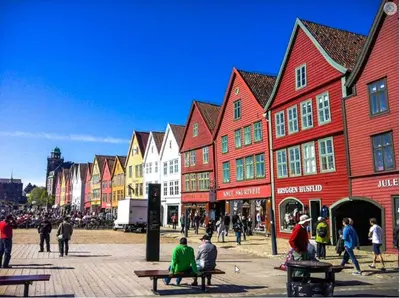 a group of people sitting on benches in a street with buildings at Cozy apartment in City Center in Bergen