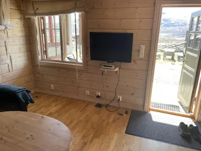 a living room with a television in a log cabin at Syndinstøga in Ryfoss