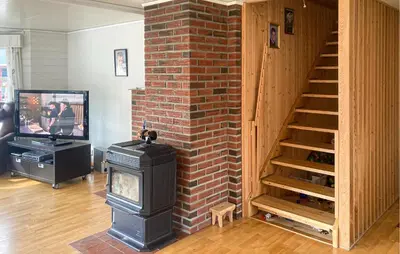a living room with a brick fireplace and a staircase at 4 Bedroom Nice Home In Flornes in Flornes