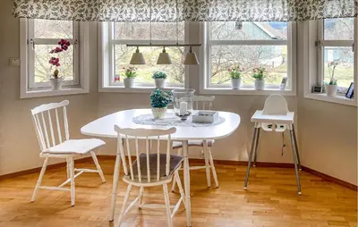 a white table and chairs in a room with windows at 4 Bedroom Nice Home In Flornes in Flornes