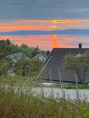 a house with a roof on the shore of a body of water at Lite hus i hagen in Malvik