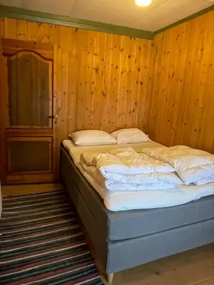 a bed in a room with a wooden wall at Koselig tømmerhus på gammel gård i Skåbu in Graupe