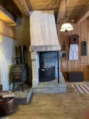a stone fireplace in a room with a stove at Koselig tømmerhus på gammel gård i Skåbu in Graupe