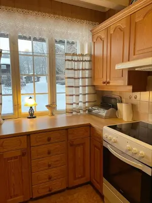 a kitchen with wooden cabinets and a table with a lamp at Koselig tømmerhus på gammel gård i Skåbu in Graupe