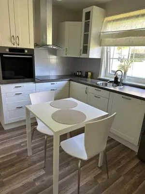 a white kitchen with a white table and chairs at Maria apartment with Sauna Otta in Otta