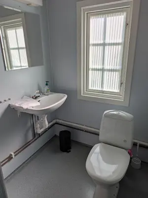 a bathroom with a white toilet and a sink at Myrland Apartments in Hovet