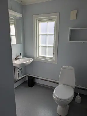 a bathroom with a white toilet and a sink at Myrland Apartments in Hovet