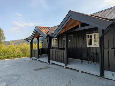 a black cabin with a porch and a table at Myrland Apartments in Hovet