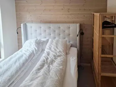a bedroom with a white bed and a wooden shelf at Near-Sea Boat House With Panoramic Views in Sykkylven