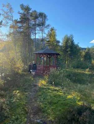 two people walking towards a gazebo in a field at Hafslo hytteutleige Straumane in Hafslo
