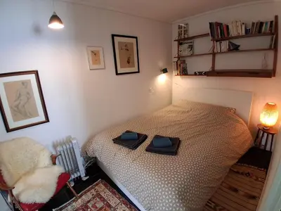 a small bedroom with a bed and a chair at Appartement calme et central sur Bergen in Bergen