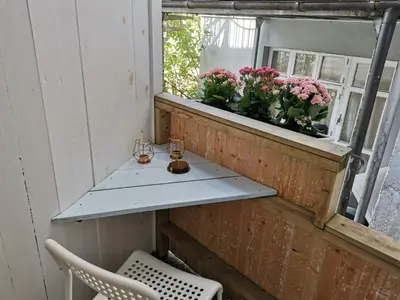 a balcony with a table and flowers in a window at Super cozy 3-bedroom in picturesque neigborhood in Bergen
