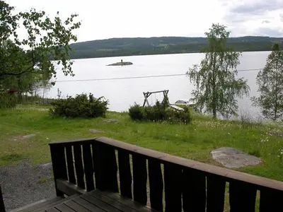 a bench sitting next to a body of water at Hagali by Norgesbooking - cabin by the lake Næra, close to Sjusjøen in Ringsaker