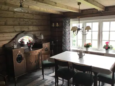a dining room with a table and some windows at Gamlemgarden by Norgesbooking - house by the sea in Longva