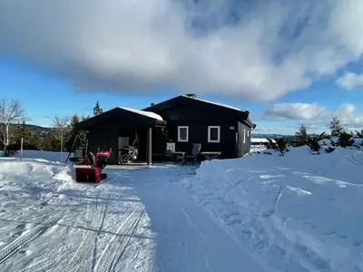 a small cabin in the snow with a red sled at Family Cabin With Views In Valdres in Reinli
