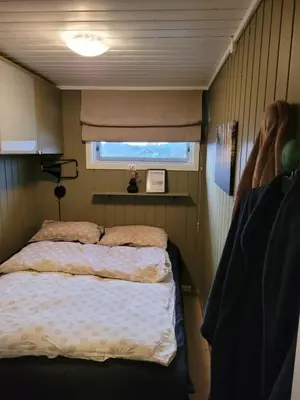 a small bedroom with a bed and a window at Emberland vannet , sveio in Sveio