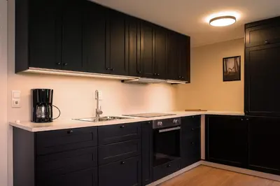 a kitchen with black cabinets and a sink at Leilighet sentralt i Bud in Bud