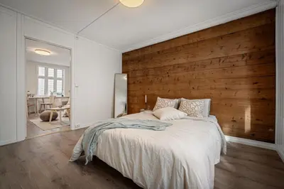 a bedroom with a large bed with a wooden wall at Bergen style Apt I Cozy street I Easy check in in Bergen