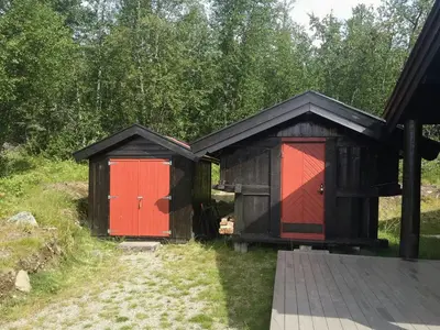 two outbuildings with red doors in a yard at Modern Log Cabin By Hardangervidda in Dagali