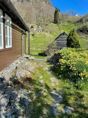 a house with a field of flowers next to a building at Historic Farm With Sea View Over Bjørnefjorden
